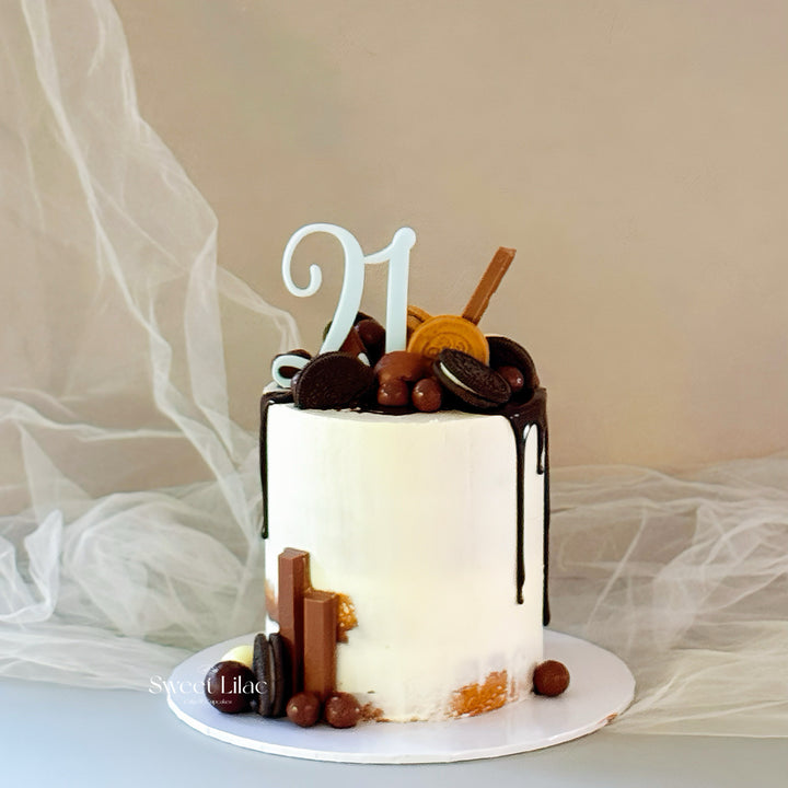 Small cake with chocolate drizzle and decorative elements on a neutral background