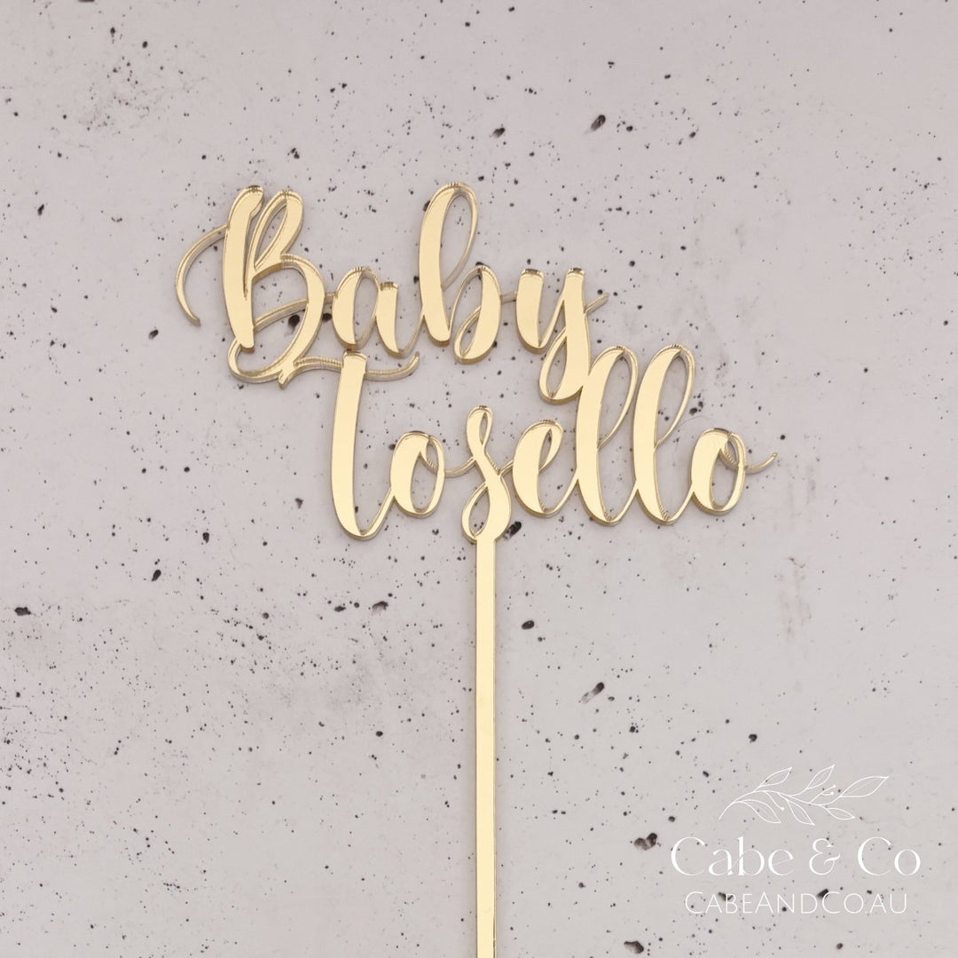 A gold metallic script cake topper reading &