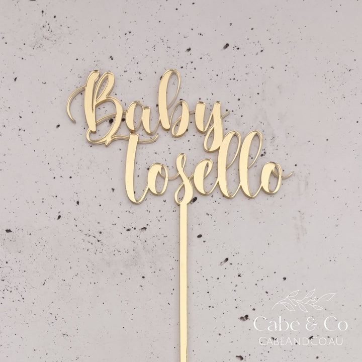 A gold metallic script cake topper reading &