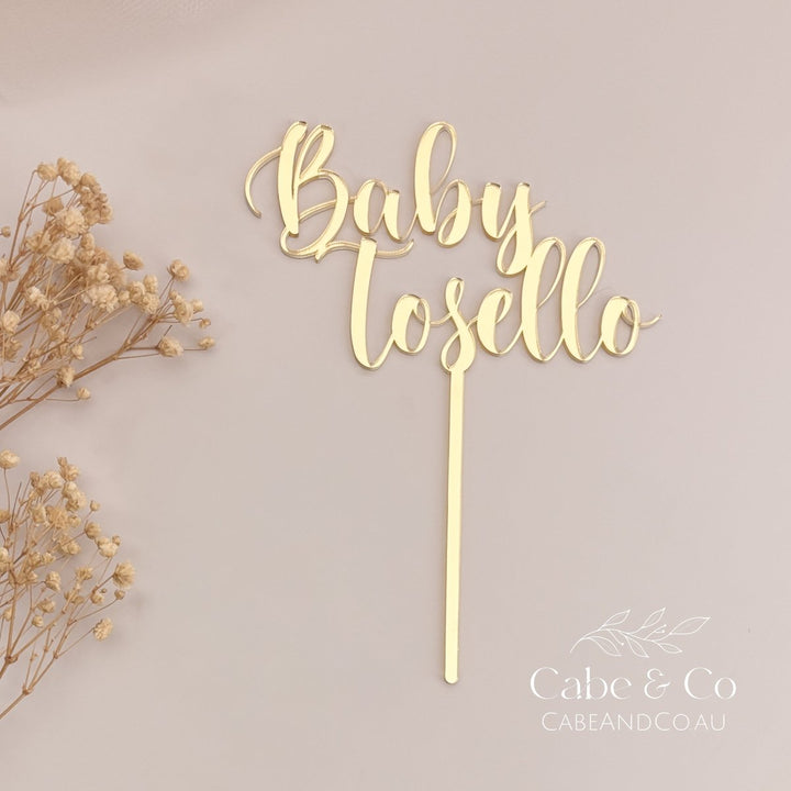 A gold acrylic cake topper with the personalized name &